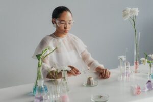 Scientist experimenting with flowers and glassware, blending science and nature in a studio setting.