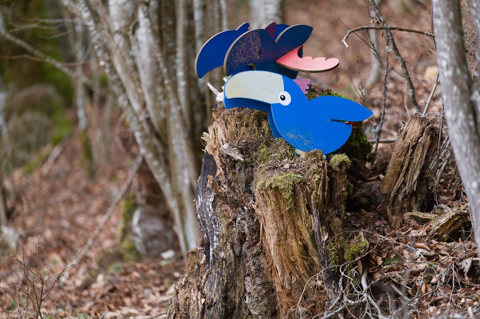 Vibrant bird sculpture perched on a tree stump amidst a serene forest.