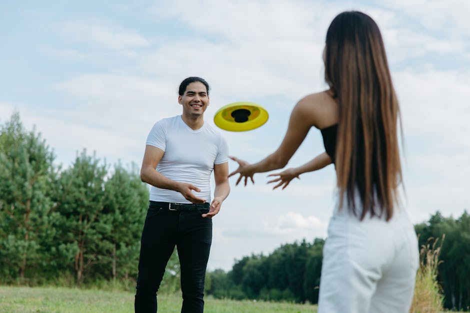 A joyful couple enjoying a playful frisbee game in a lush green park outdoors.