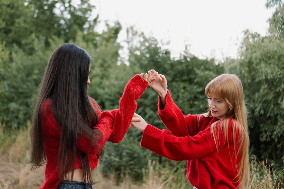 Two women in red sweaters enjoying a playful moment in a lush outdoor setting. Captured in Germany.