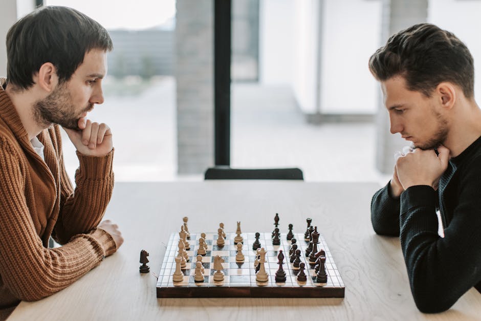 Two adults deeply engaged in a strategic chess match on a wooden table indoors.