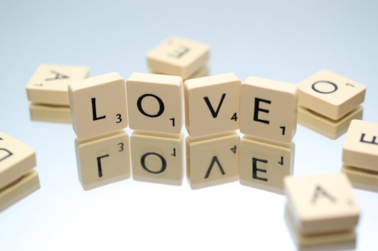 Scrabble tiles spelling LOVE on reflective surface, creating conceptual design.