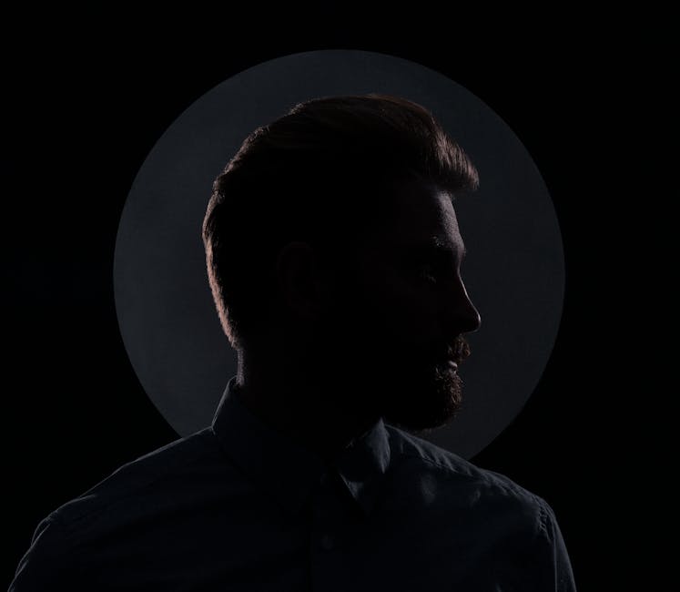 Moody silhouette profile of a man against a dark background with a circular spotlight.