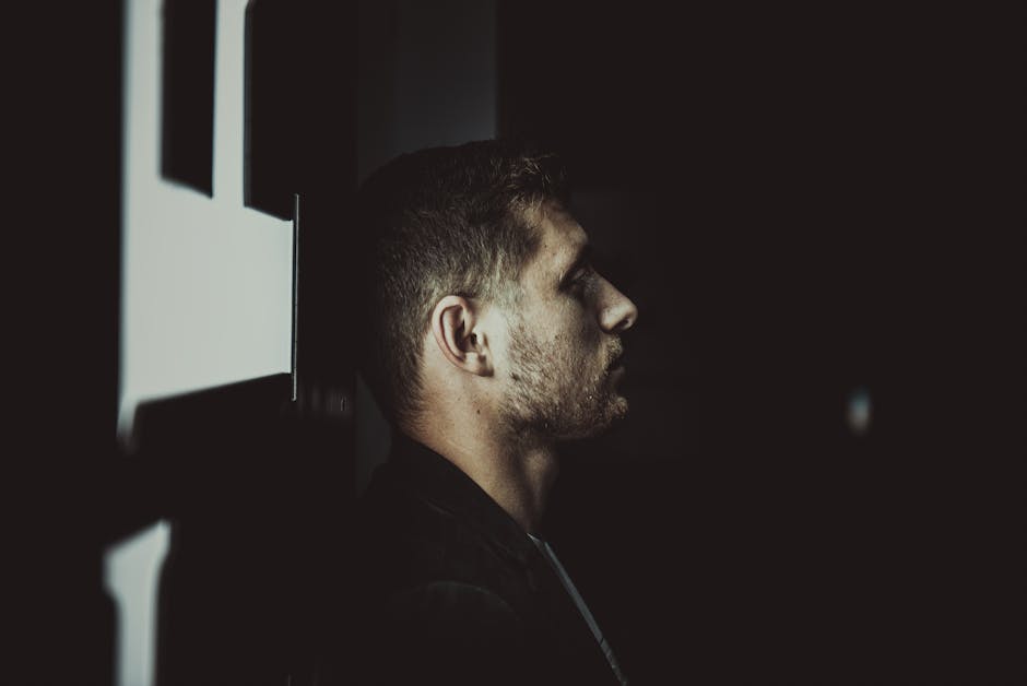 Dramatic side profile of a bearded man in a shadowy studio setting, evoking mystery.