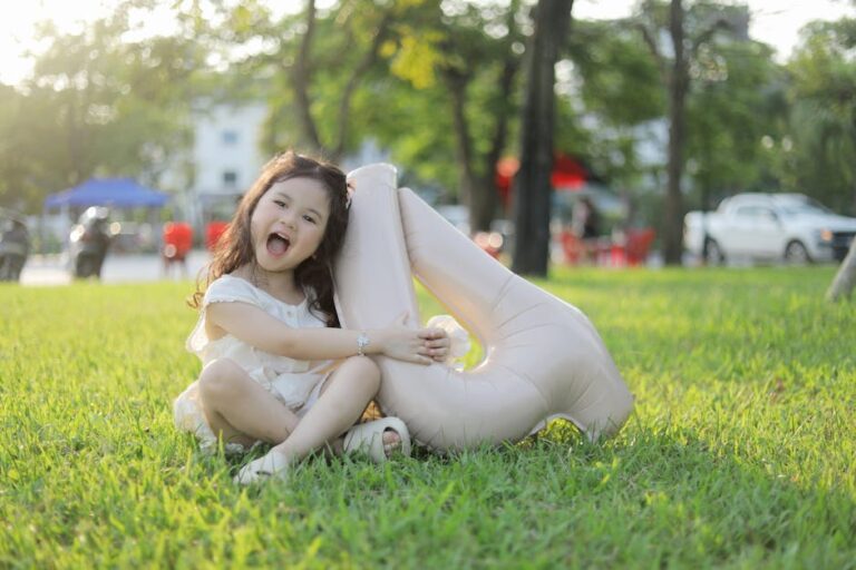 Happy child sitting on grass with a balloon, celebrating outdoors in Bắc Ninh, Vietnam.