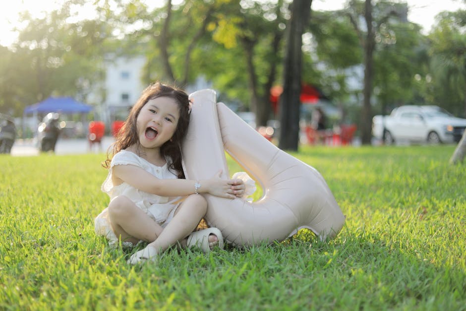 Happy child sitting on grass with a balloon, celebrating outdoors in Bắc Ninh, Vietnam.