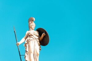 A photo of the Athena statue in Athens, showcasing its intricate details against a bright blue sky background.