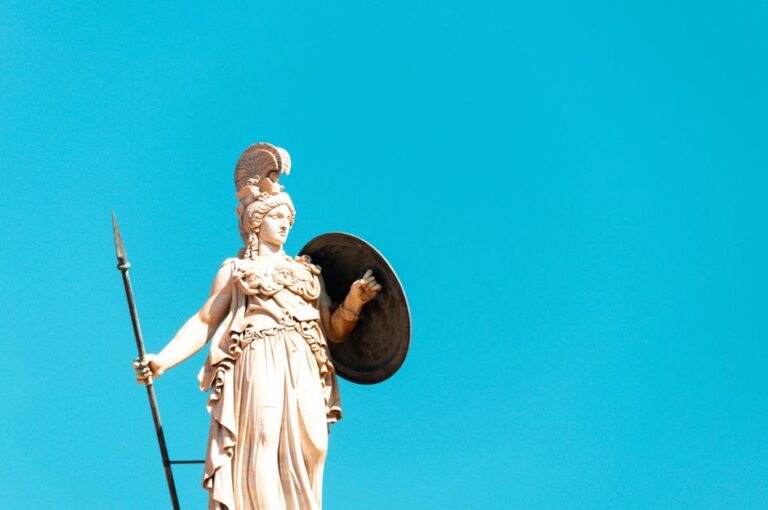 A photo of the Athena statue in Athens, showcasing its intricate details against a bright blue sky background.