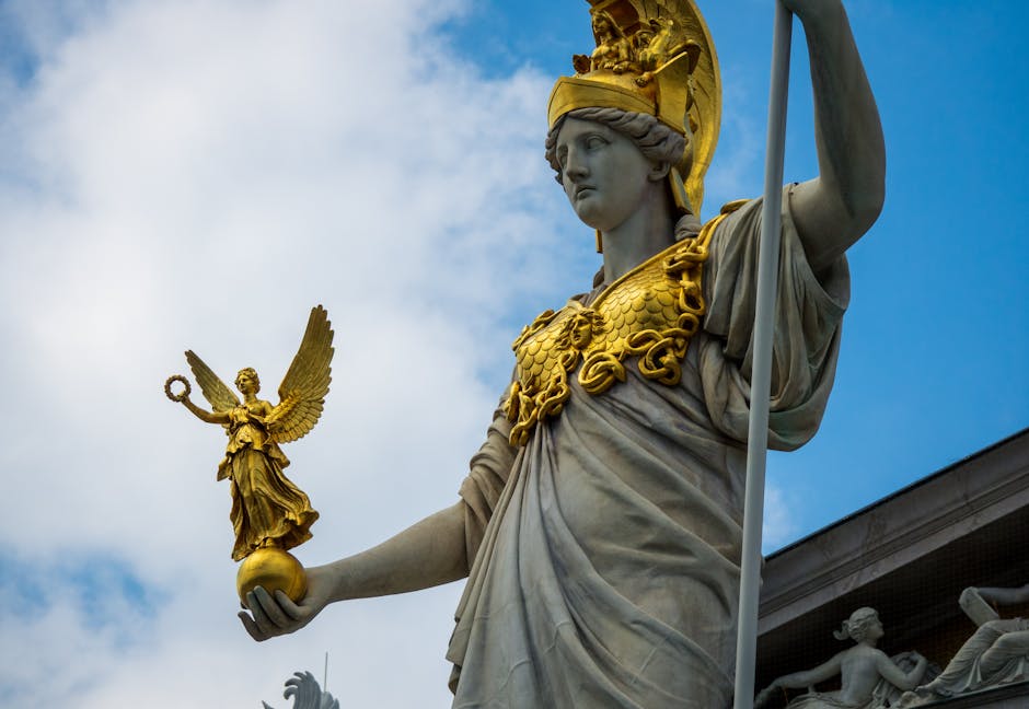 Ornate Greek goddess statue with golden accents against blue sky in Vienna, Austria.