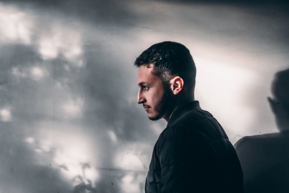Side profile of a contemplative man with shadows on the wall, exuding a moody vibe.