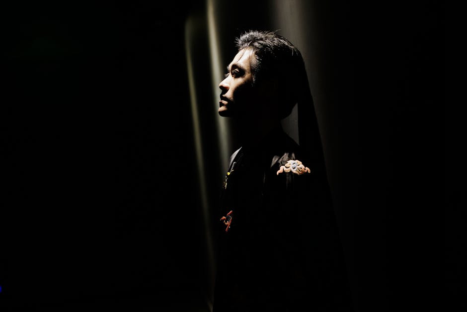 Profile portrait of a man in a dramatic low light setting, creating a moody and introspective atmosphere.