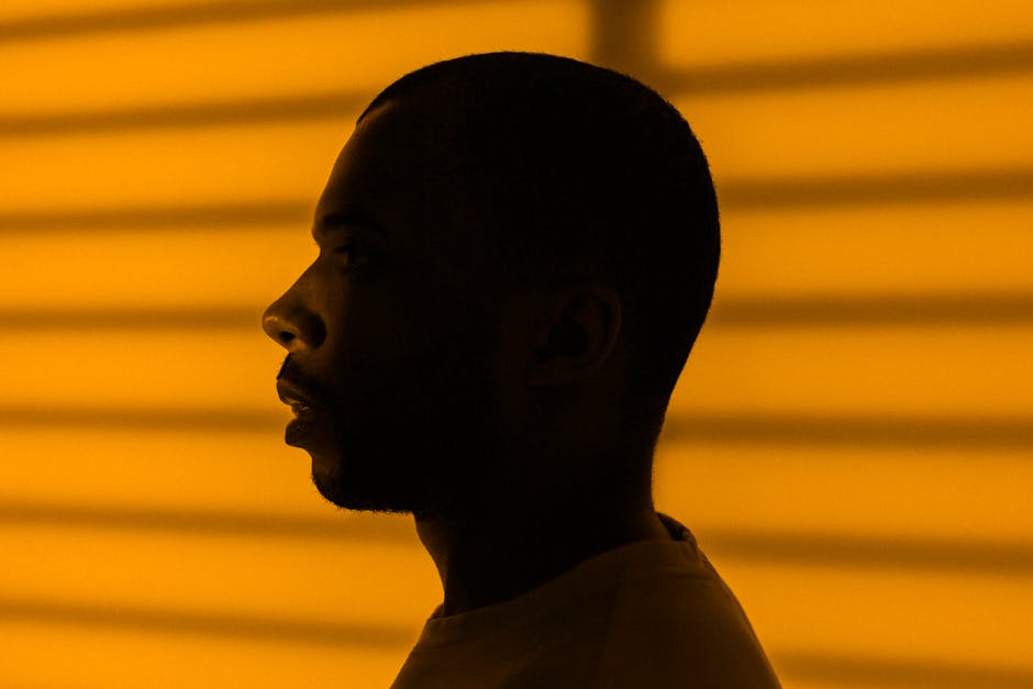 Side profile silhouette of a man with a yellow striped background, evoking a moody atmosphere.