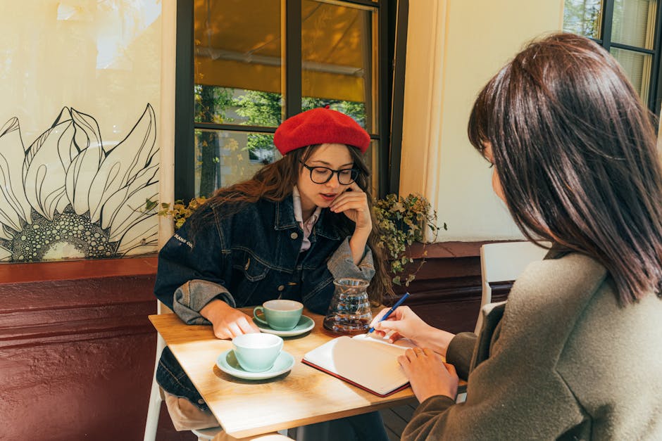 Two women having a discussion and taking notes at a chic outdoor cafe.