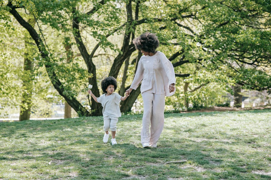 A mother and daughter enjoying a sunny day walking hand in hand in a green park.
