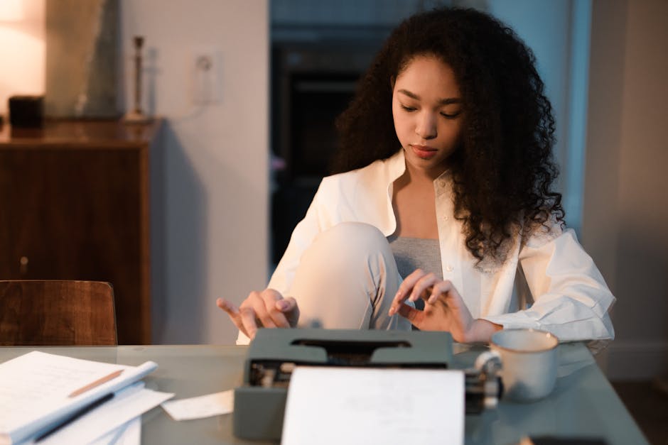 A young woman typing on a vintage typewriter at a desk with papers indoors.