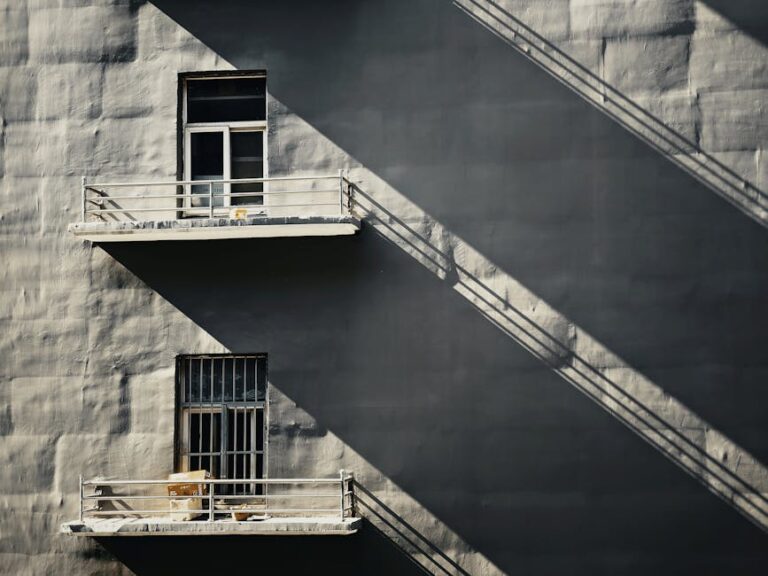 Minimalist architecture with striking shadows on a grey concrete facade, showcasing urban design.
