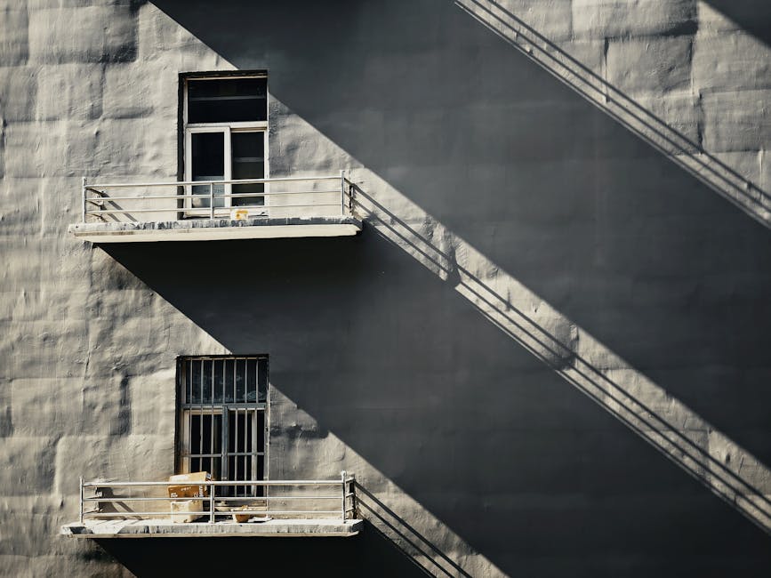 Minimalist architecture with striking shadows on a grey concrete facade, showcasing urban design.