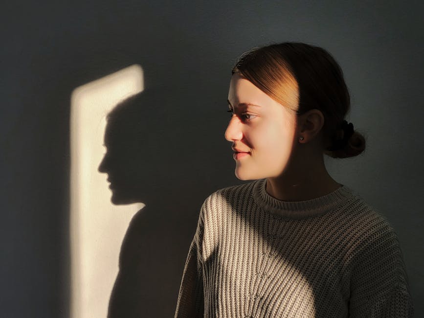 Woman in a sweater bathed in sunlight, creating dramatic shadow effect.