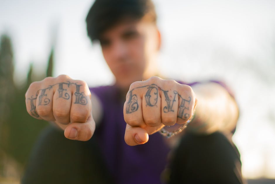 Close-up of tattooed fists showing 'Love Hate' outdoors, emphasizing self-expression.