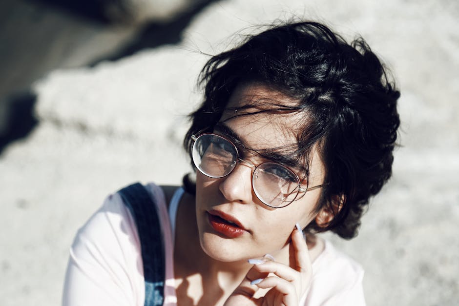 Stylish portrait of a young woman with glasses and short hair outdoors.