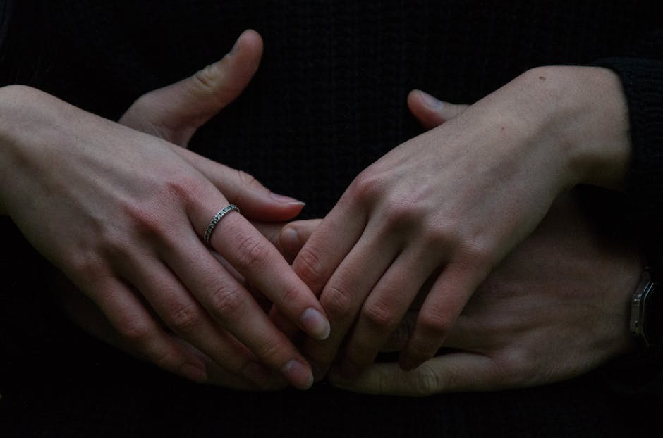 Intimate close-up of a couple's intertwined hands, one with a ring.