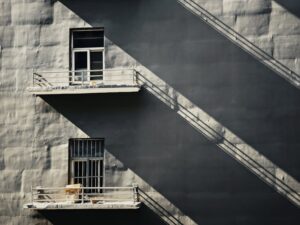 Minimalist architecture with striking shadows on a grey concrete facade, showcasing urban design.