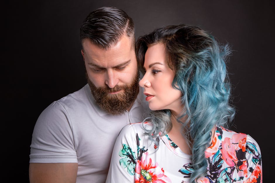 A couple embracing in a studio setting with a gray background, showcasing intimacy and style.
