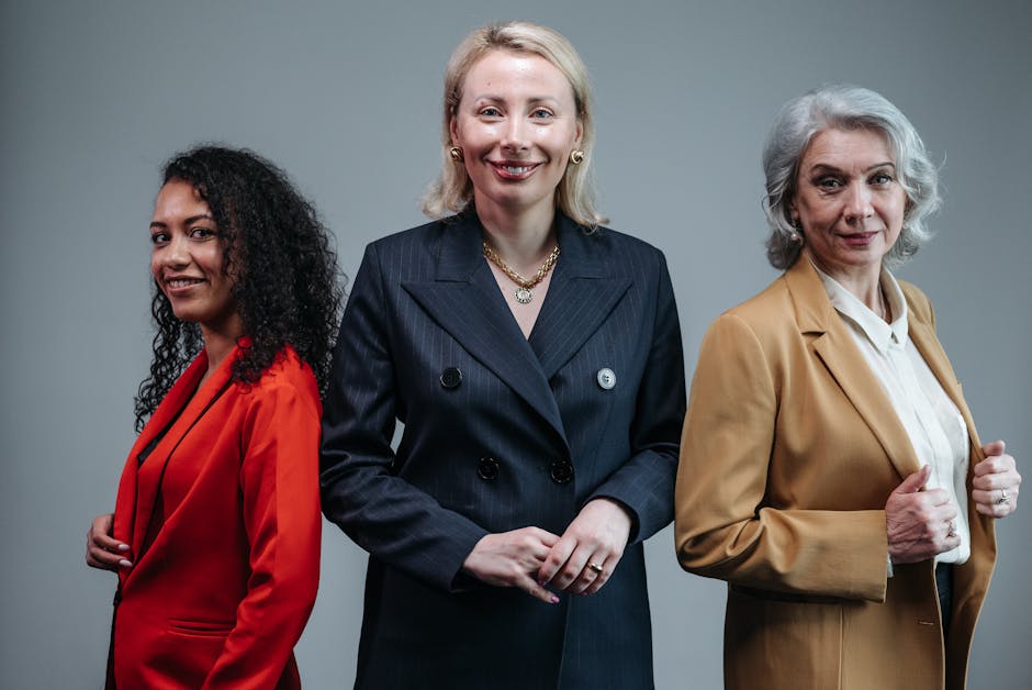 Three confident business women standing in fashionable attire, exuding professionalism.