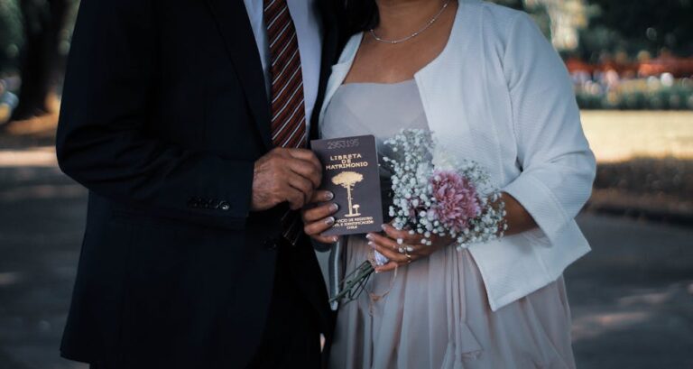 Couple holding marriage certificate and bouquet in an outdoor wedding setting.