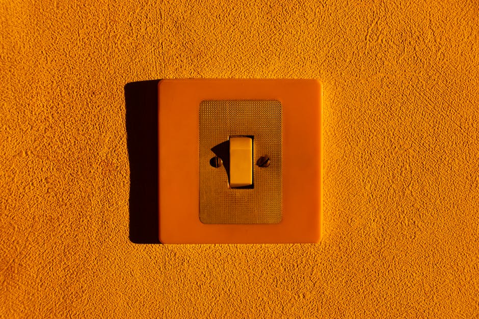 Close-up of a yellow light switch on a textured wall, highlighting minimalism.