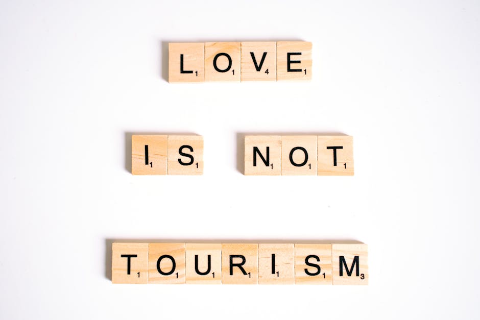 Scrabble tiles spelling 'Love is Not Tourism' on a white surface.