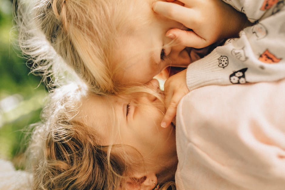 Heartwarming close-up of two blonde children playfully bonding outdoors.