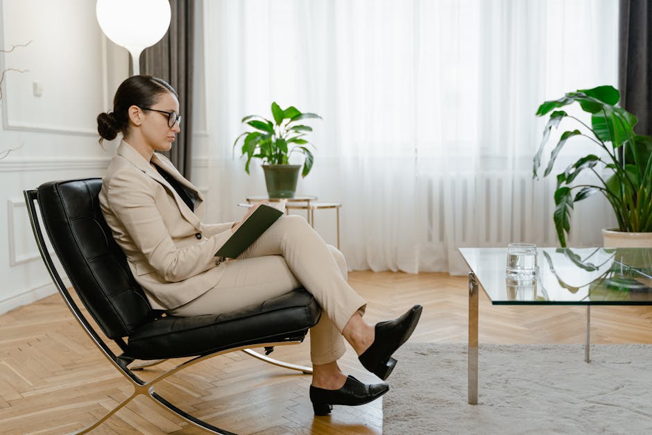 Businesswoman in a stylish office, writing on a notebook while sitting on a sleek chair.