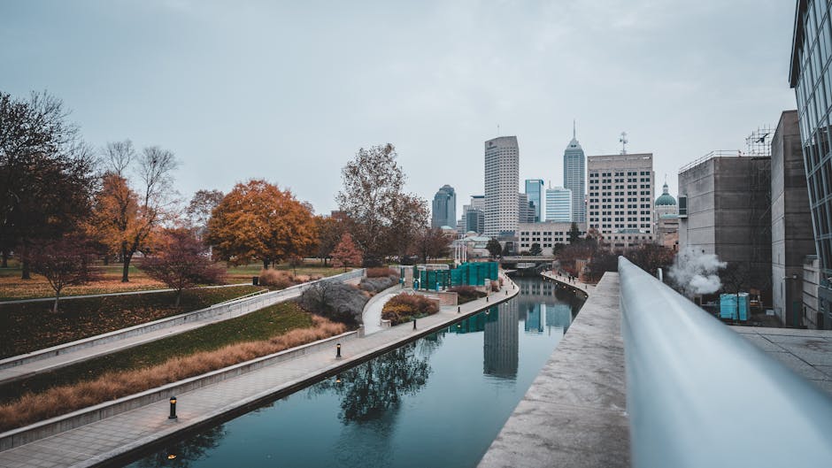 Scenic view of Indianapolis canal with city skyline and autumn colors reflecting on the water.