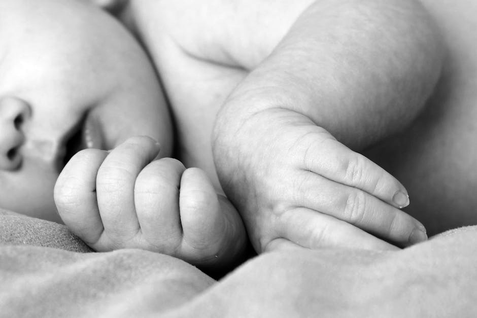Black and white close-up of a newborn baby's hands, symbolizing innocence and new life.