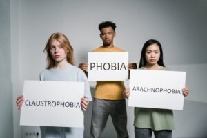 Three individuals demonstrate common phobias: arachnophobia, claustrophobia, and general fear.