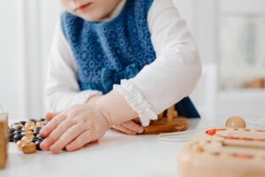A young child playing with wooden educational toys indoors, fostering creativity and learning.