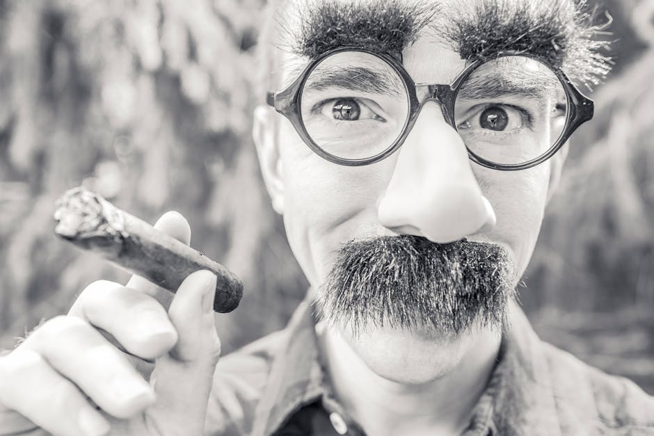 Silly portrait of a man wearing costume glasses and mustache, holding a cigar.