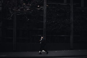 A solitary figure walks along a dimly lit urban street, capturing a moody city atmosphere.