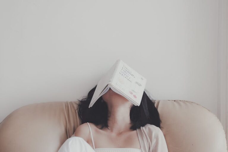 A woman relaxes indoors with an open book resting on her face, enjoying a tranquil moment.