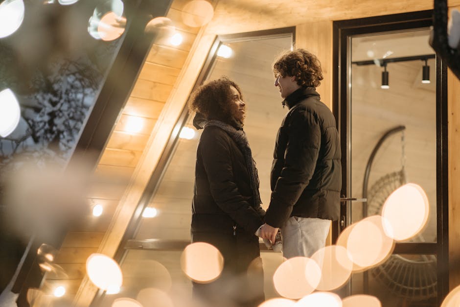 A couple standing and holding hands outdoors with romantic lights, expressing love and warmth.