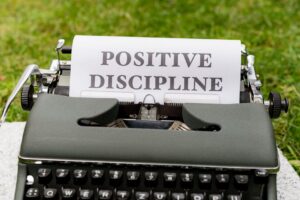 A vintage typewriter outdoors with paper showing 'Positive Discipline'.