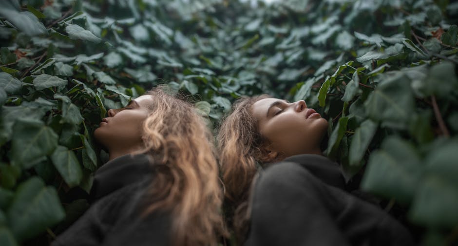 Twin women with closed eyes, surrounded by lush green leaves, exhibiting harmony with nature.