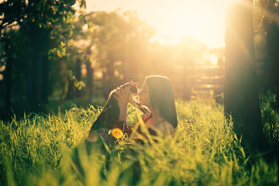 A woman lovingly embraces her pet dog in a sunlit park during sunrise.