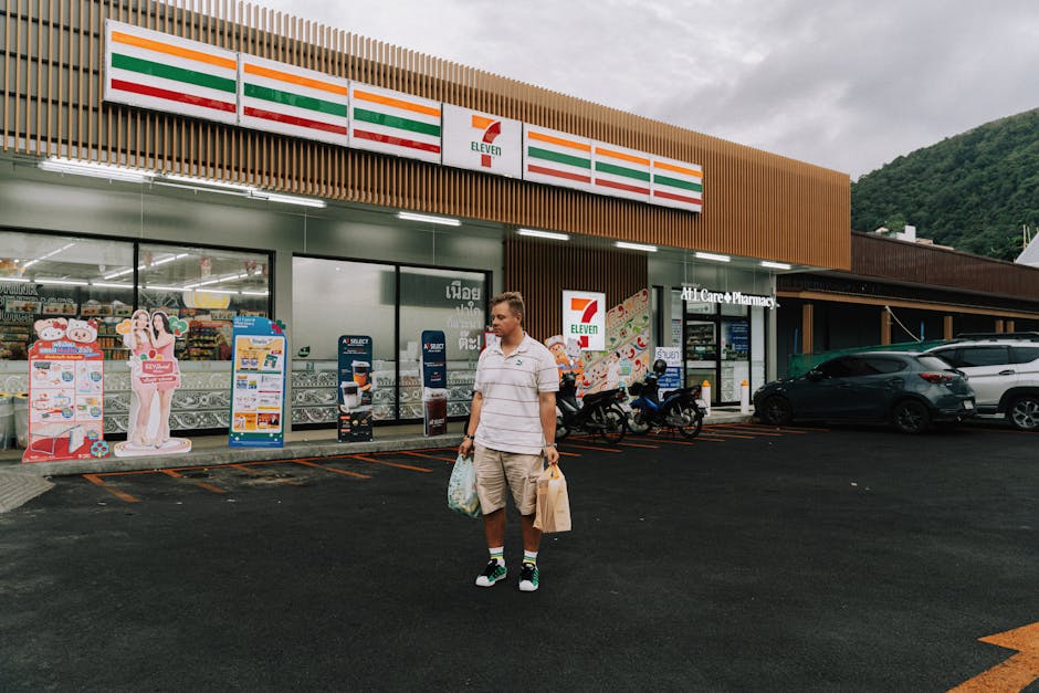 Man with shopping bags outside 7-Eleven in Phuket, showcasing a modern convenience store.