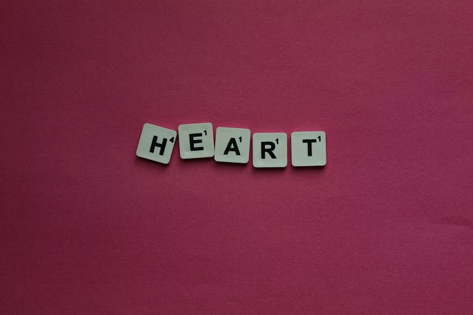 Scrabble letter tiles spelling heart on a pink background for creative projects.