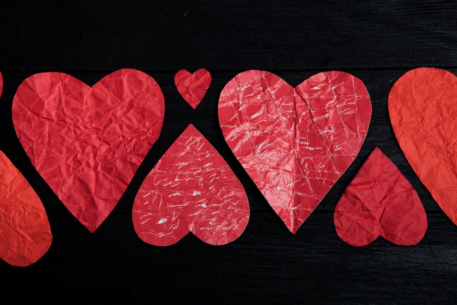Crumpled red paper hearts arranged on a black backdrop symbolizing love and romance.