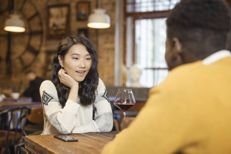 Two adults enjoying a conversation over wine in a warm, cozy café atmosphere.