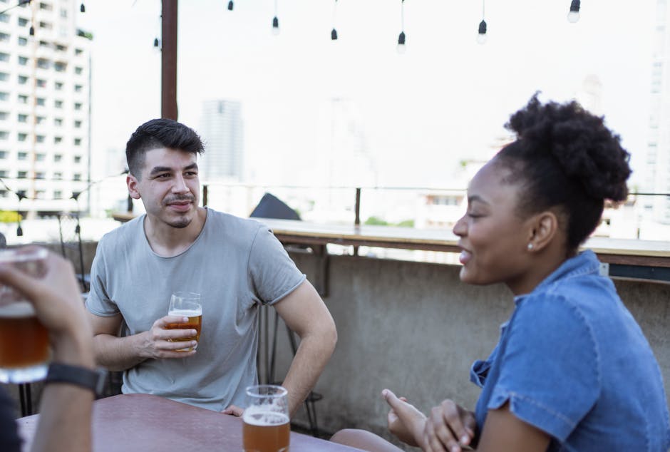 A group of friends enjoys casual conversation and drinks on a rooftop bar.