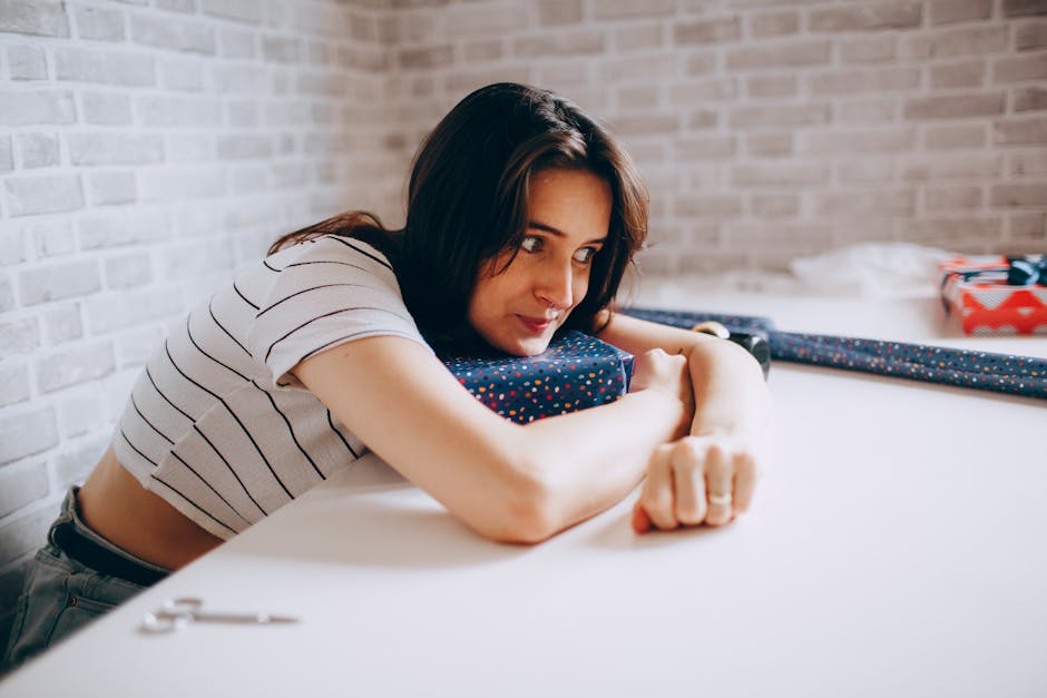 A young woman rests her arms and looks contemplative in a bright, modern indoor setting.